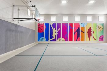 A basketball court with a wall of silhouettes of people playing different sports.